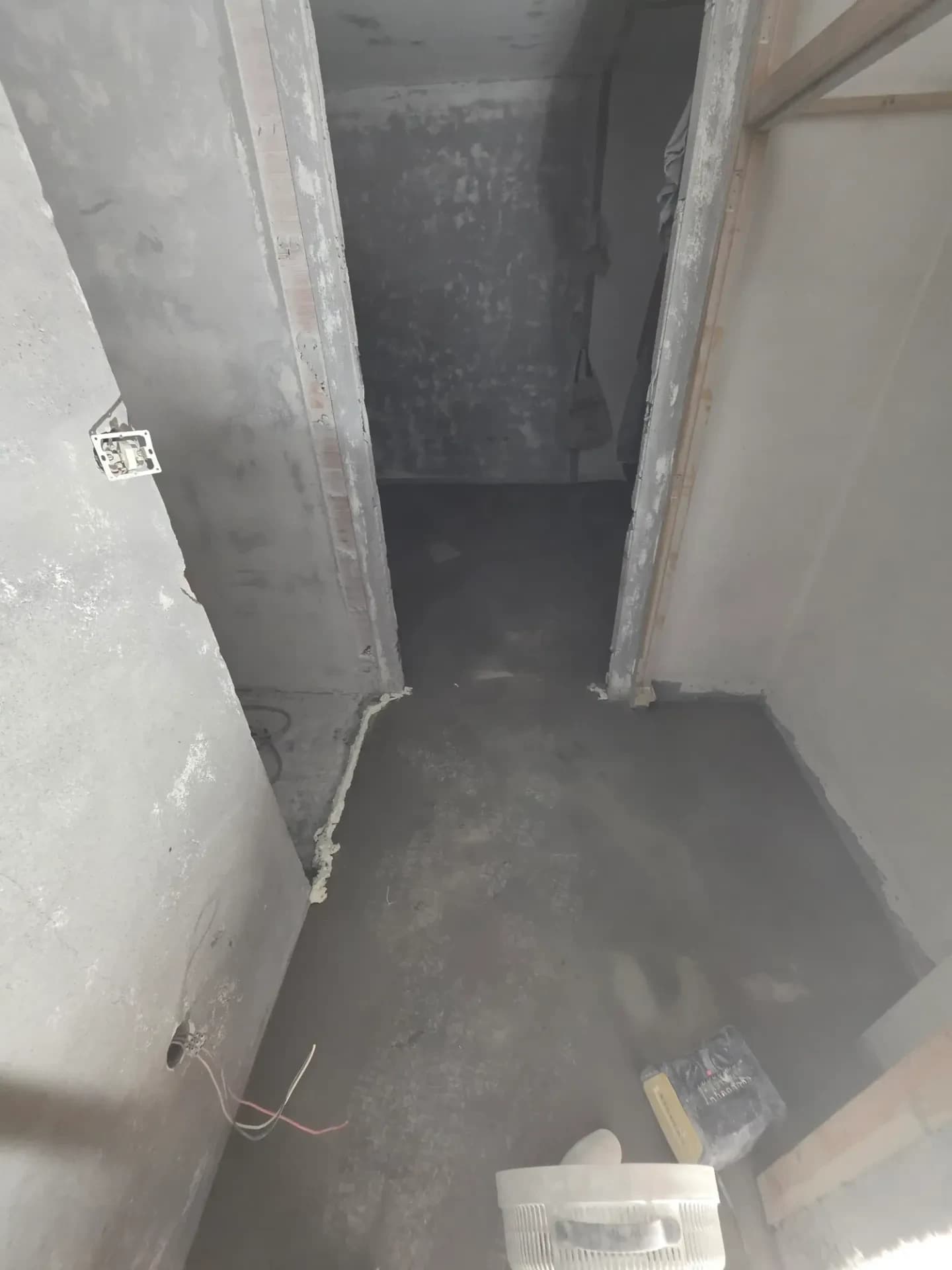 Couloir en construction, murs blancs et sol gris, appartement à Méribel, portes ouvertes et ragréage au sol