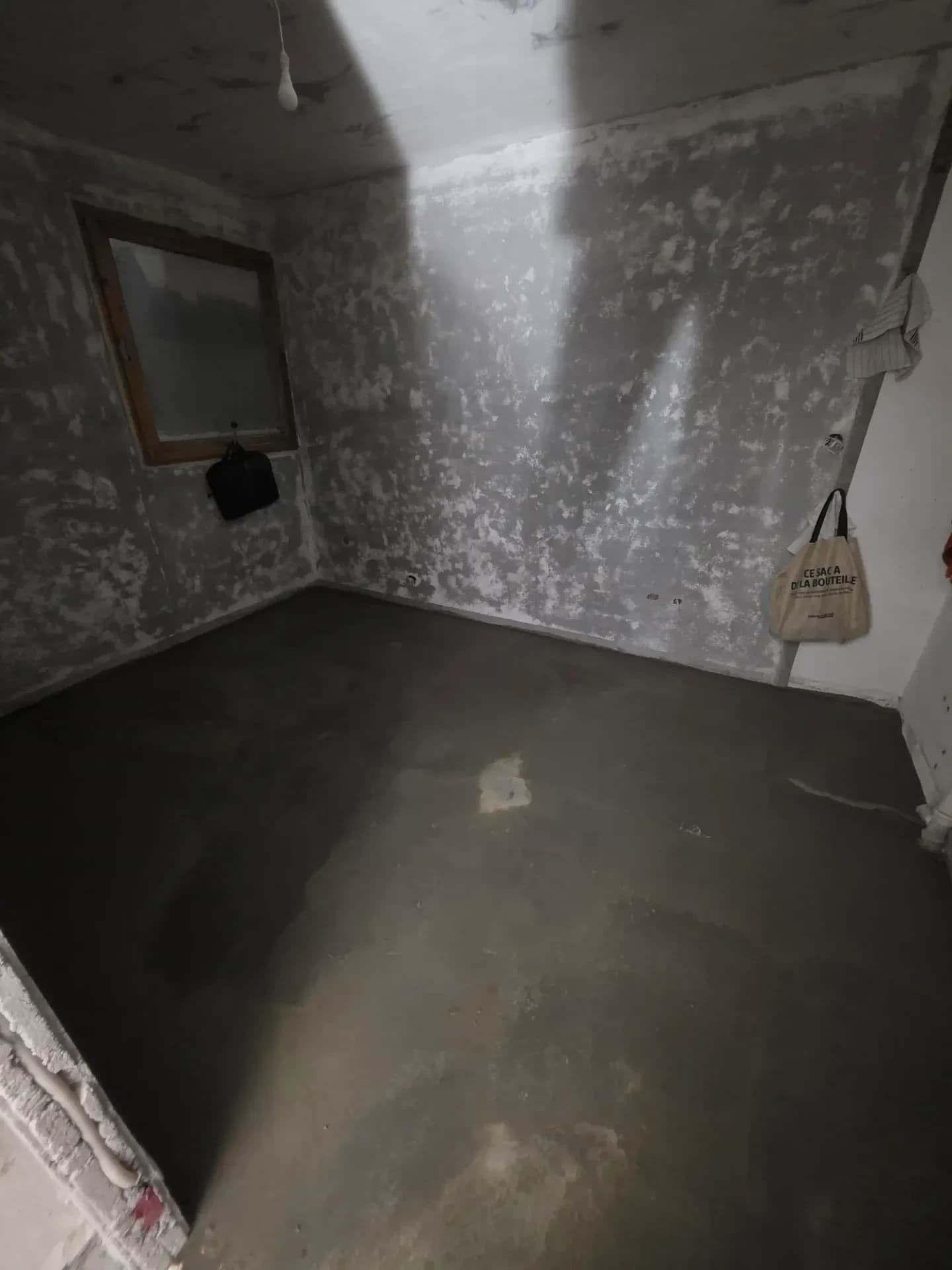 Pièce en travaux à Méribel, murs à nu gris, sol ragréé, fenêtre