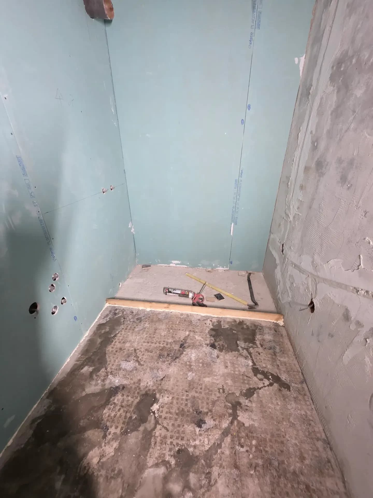 La salle de bain de l'appartement situé à Méribel, avec murs placo, sol en béton, niveau laser et outils posés au sol.