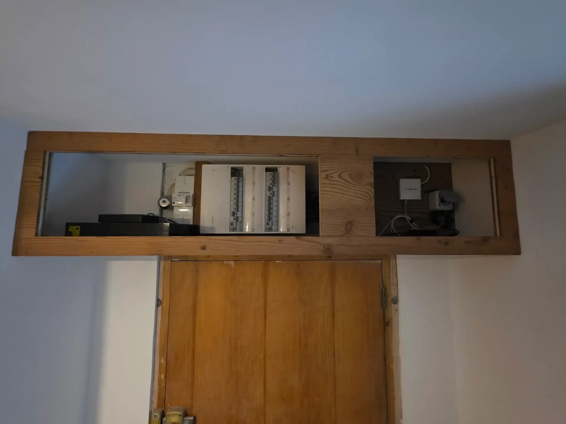 Coffret en bois ouvert montrant des équipements électriques, câbles et modules dans deux compartiments.